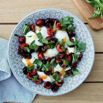 Burrata salad with cherries and hot honey in bowl on table