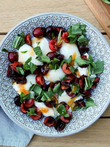Burrata salad with cherries and hot honey in bowl on table