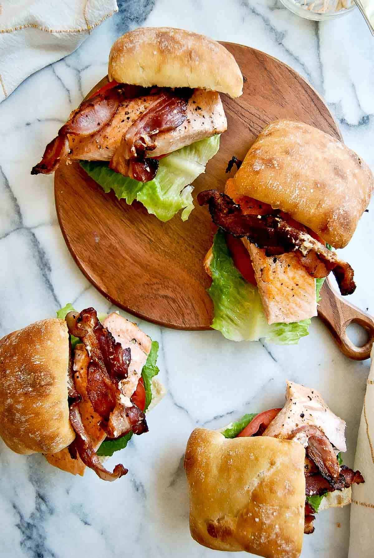salmon blt sandwiches on counter and cutting board.