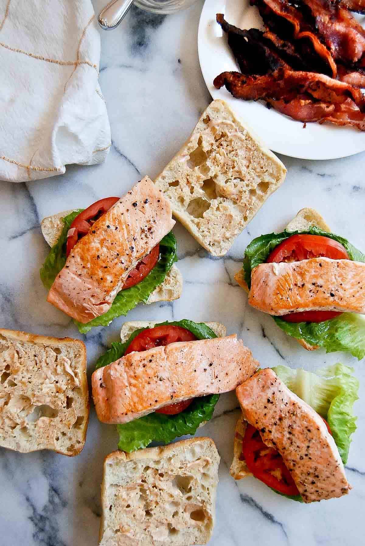 salmon pieces on buns with tomato and lettuce.