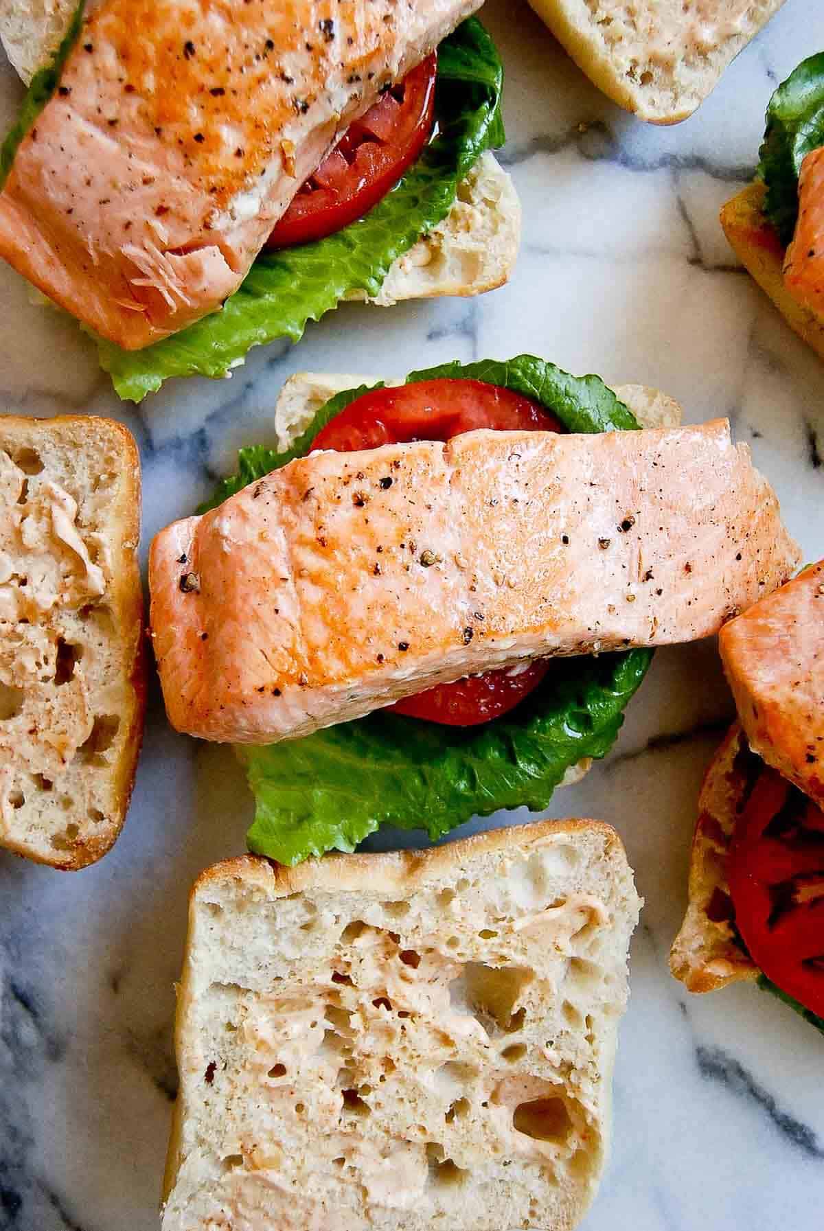 assembly of salmon blt sandwiches.