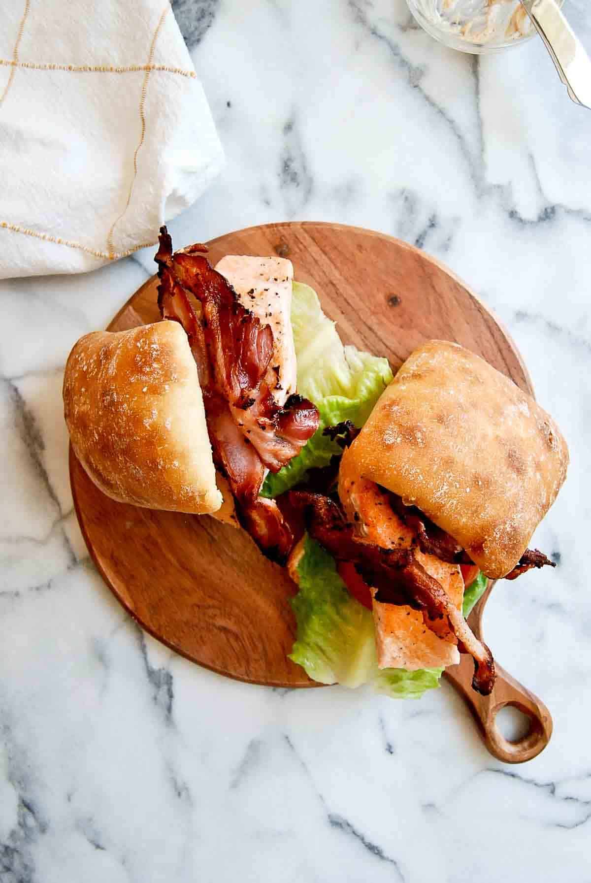 salmon blt sandwiches on cutting board.