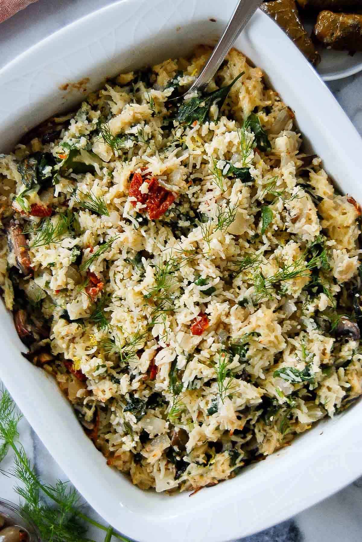 closeup of spinach feta & rice casserole in serving dish with dill on top.