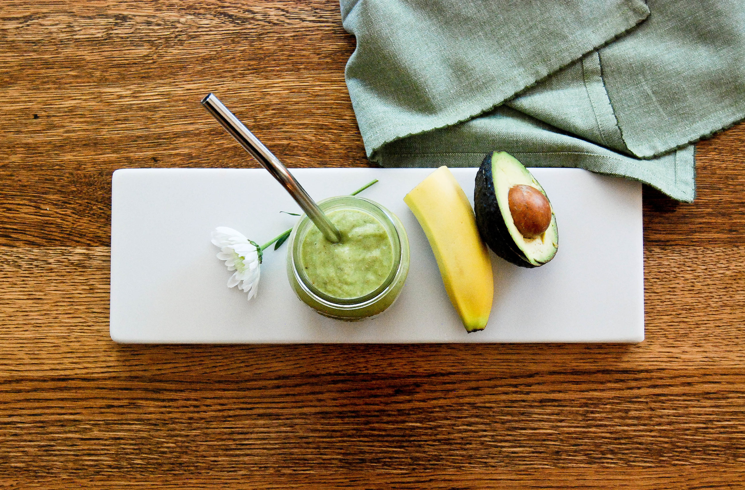 Avocado smoothie on cutting board with banana and avocado.