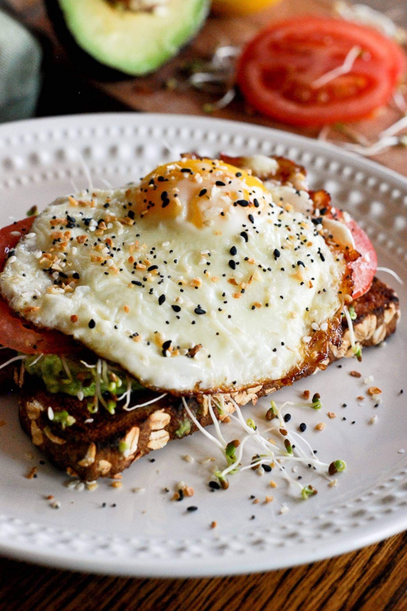 avocado toast with egg and tomato on plate.