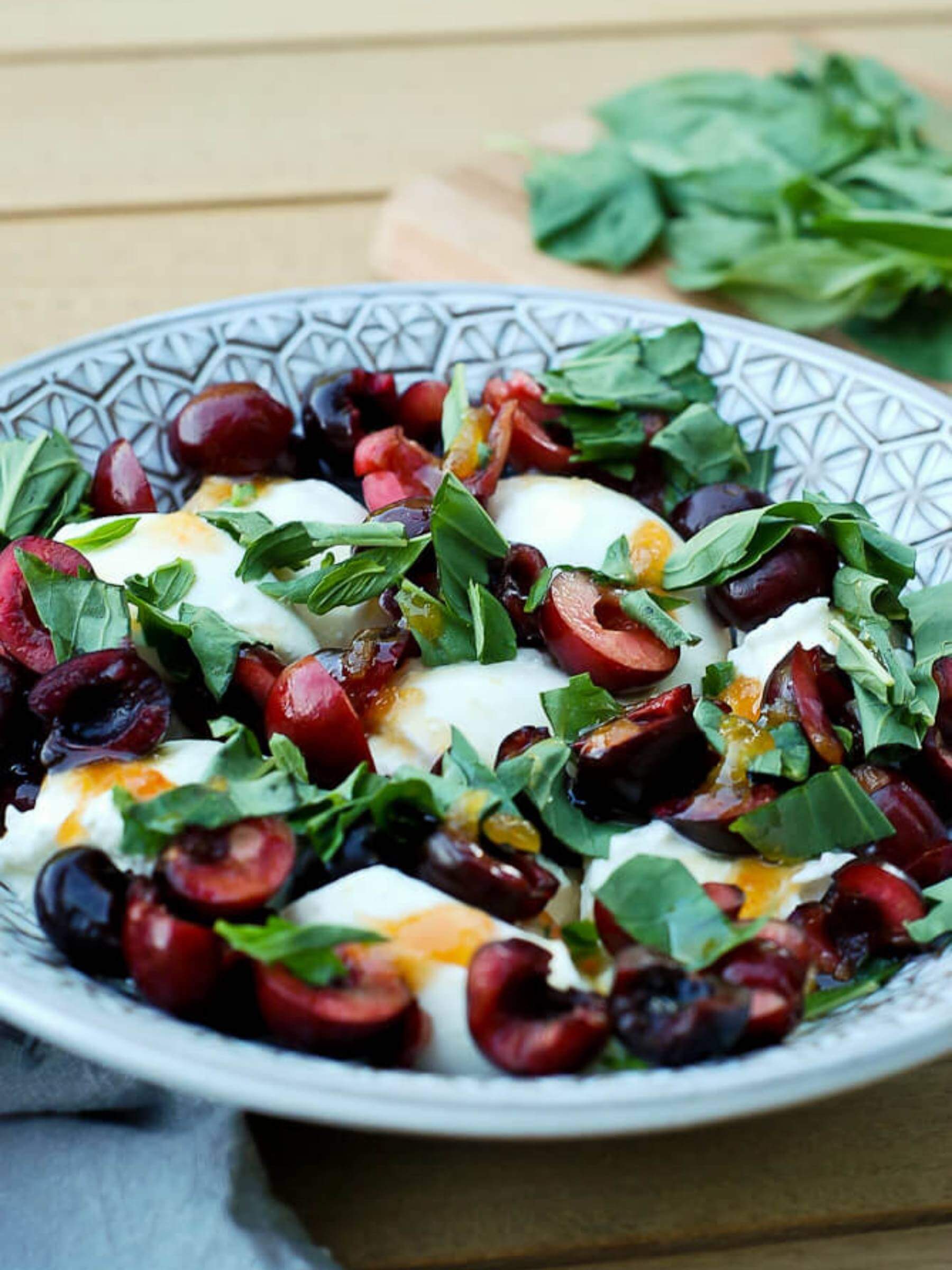 burrata, cherries and basil in bowl with honey.