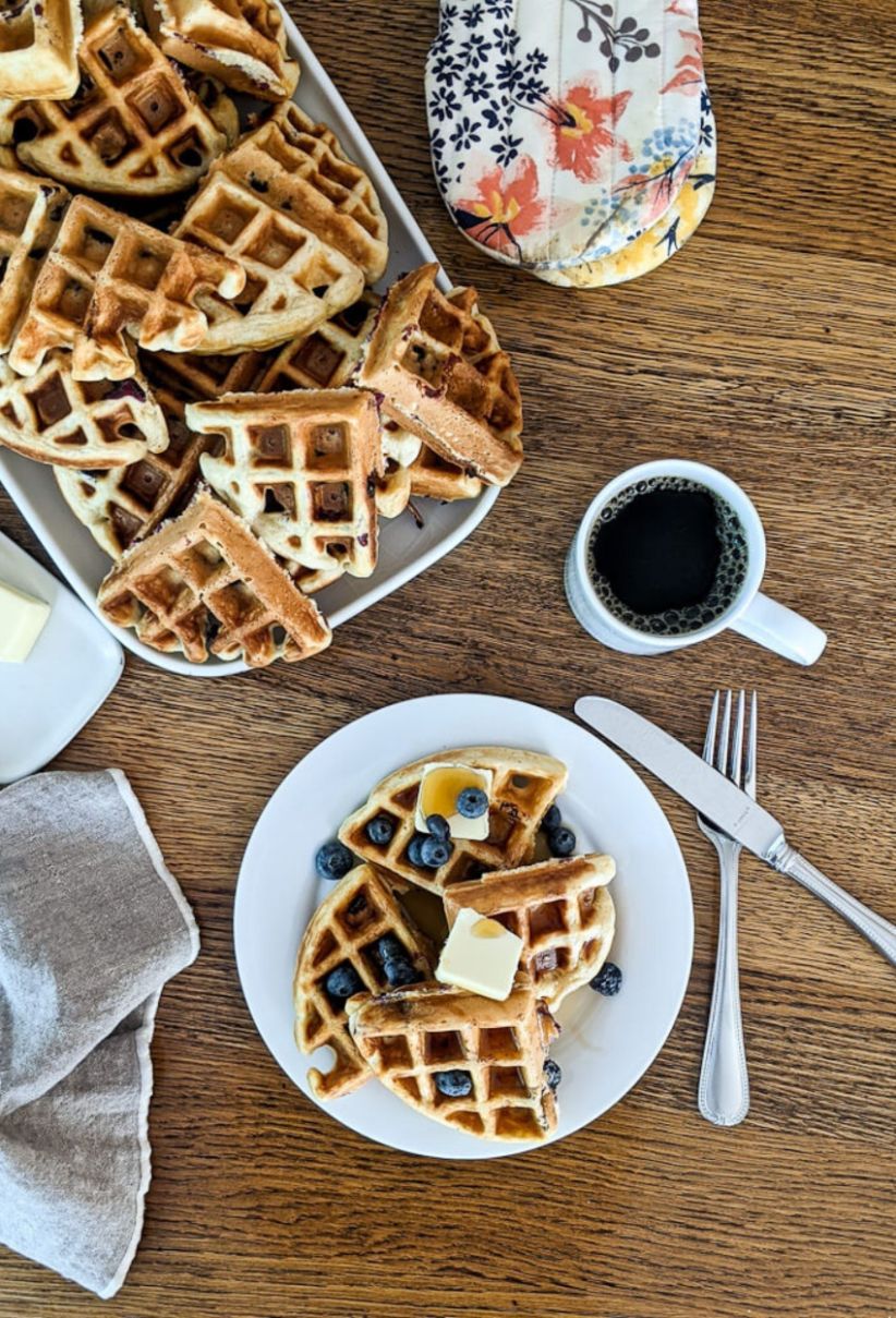 Homemade blueberry waffles plate, on breakfast table with coffee.