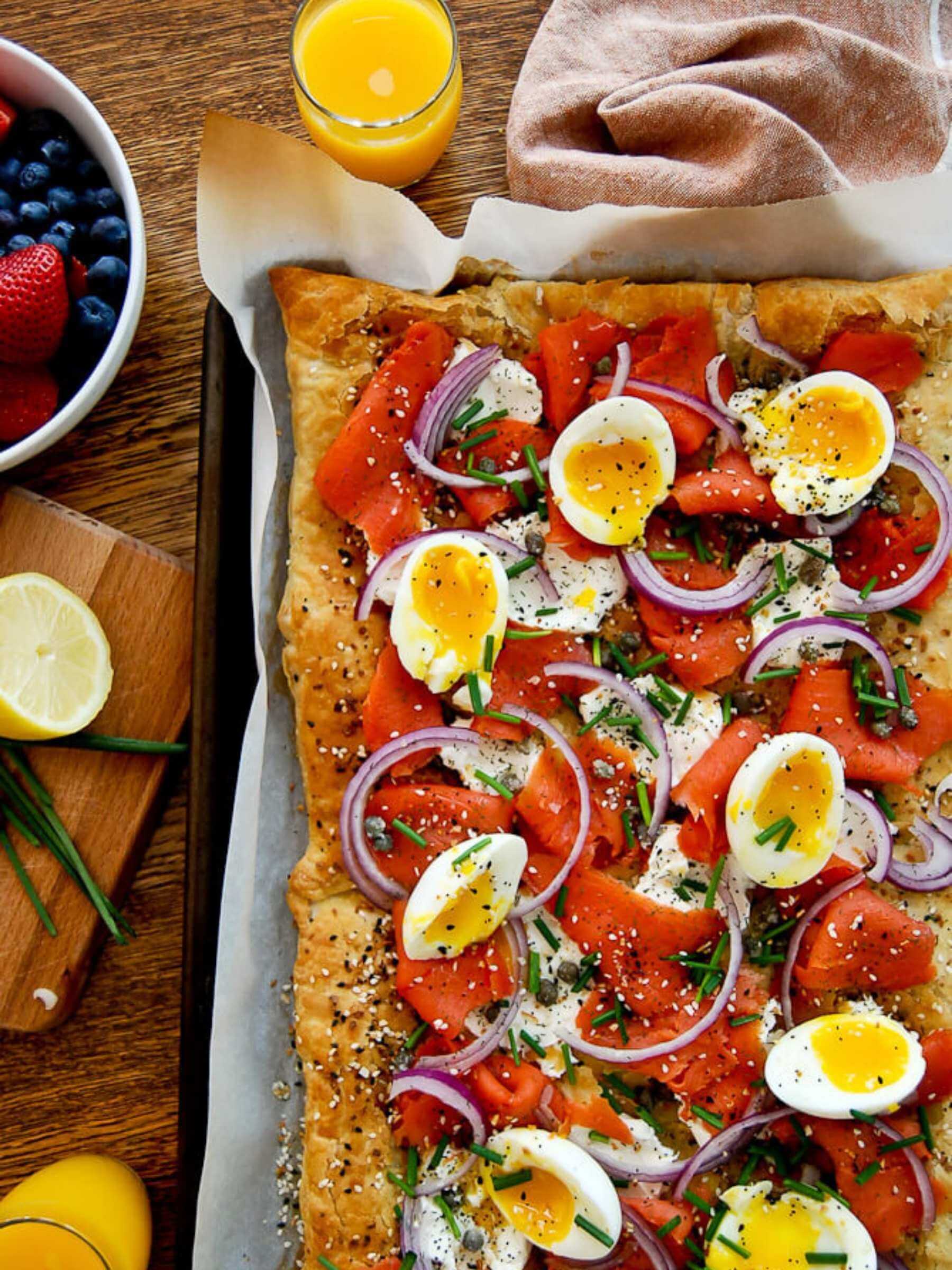 Corner of smoked salmon pizza with cream cheese, everything bagel, and soft eggs.