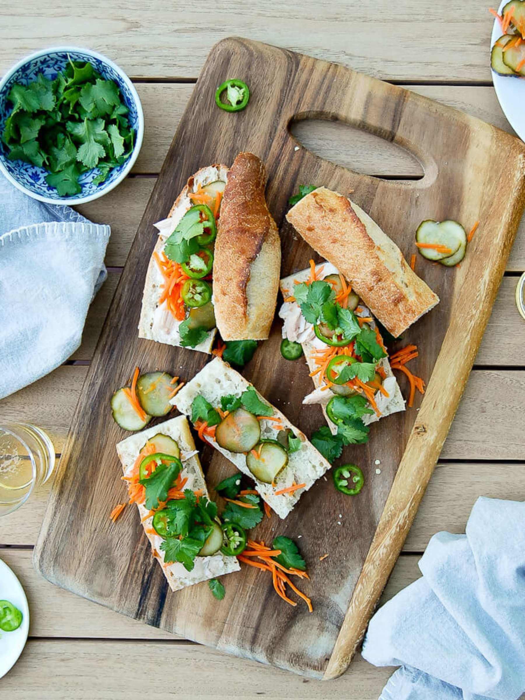 chicken banh mi sandwiches arranged open-faced on serving board.