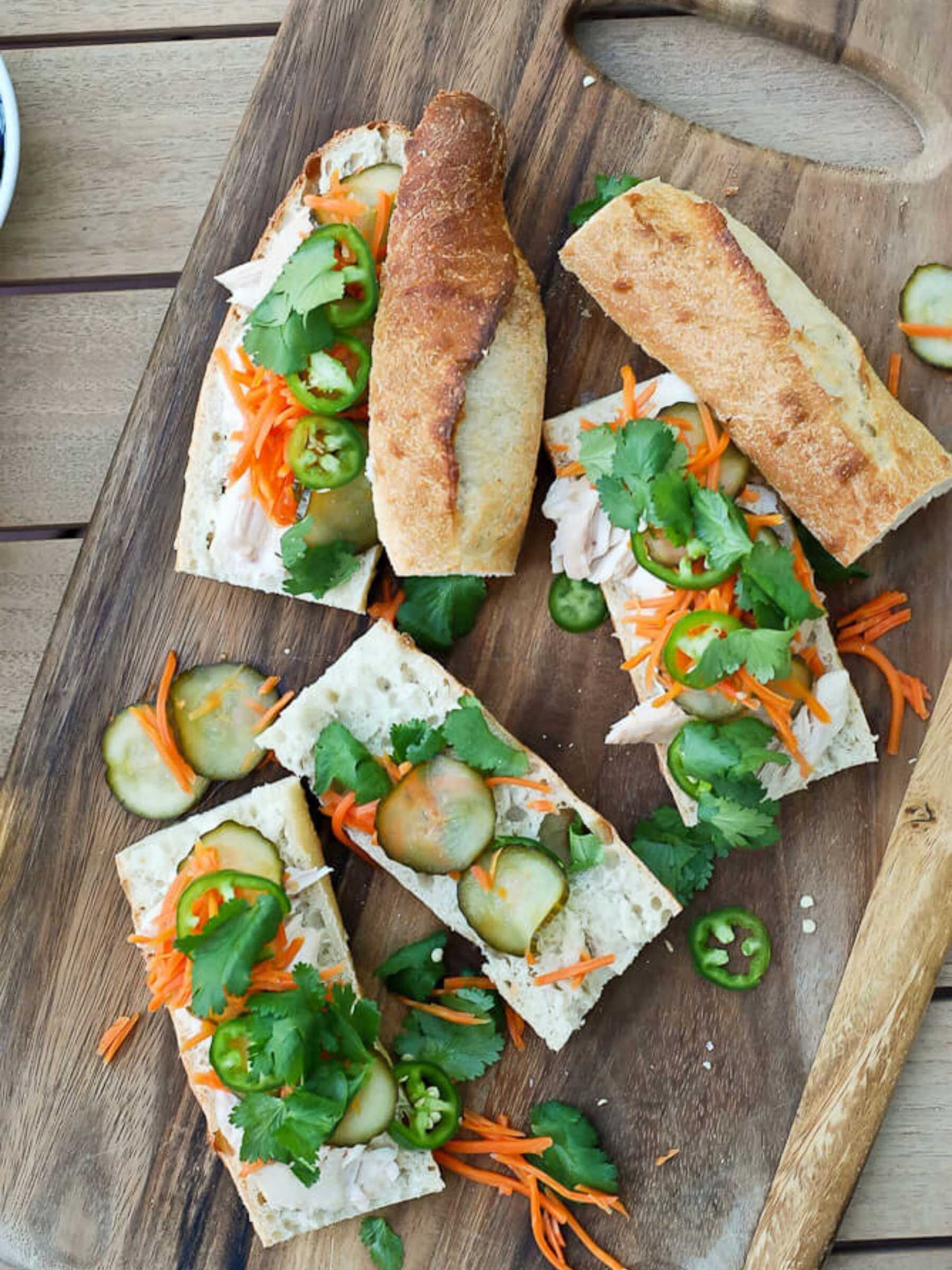 chicken banh mi sandwiches with pickled veggies on cutting board.