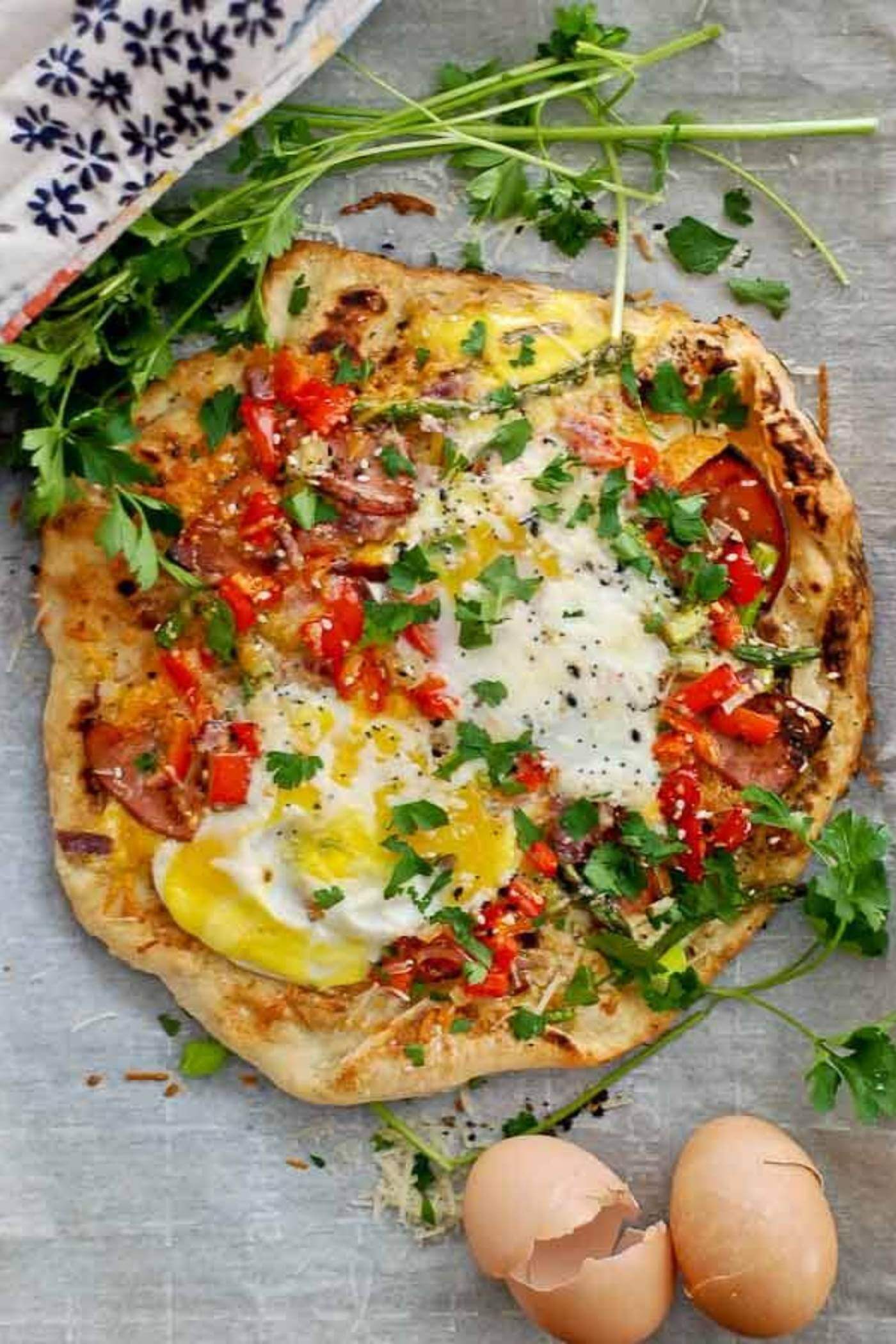 Breakfast pizza with eggs on parchment paper.