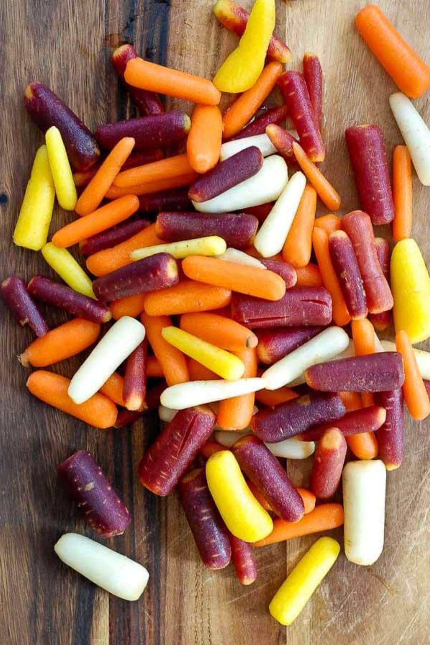 multi-colored carrots on cutting board.