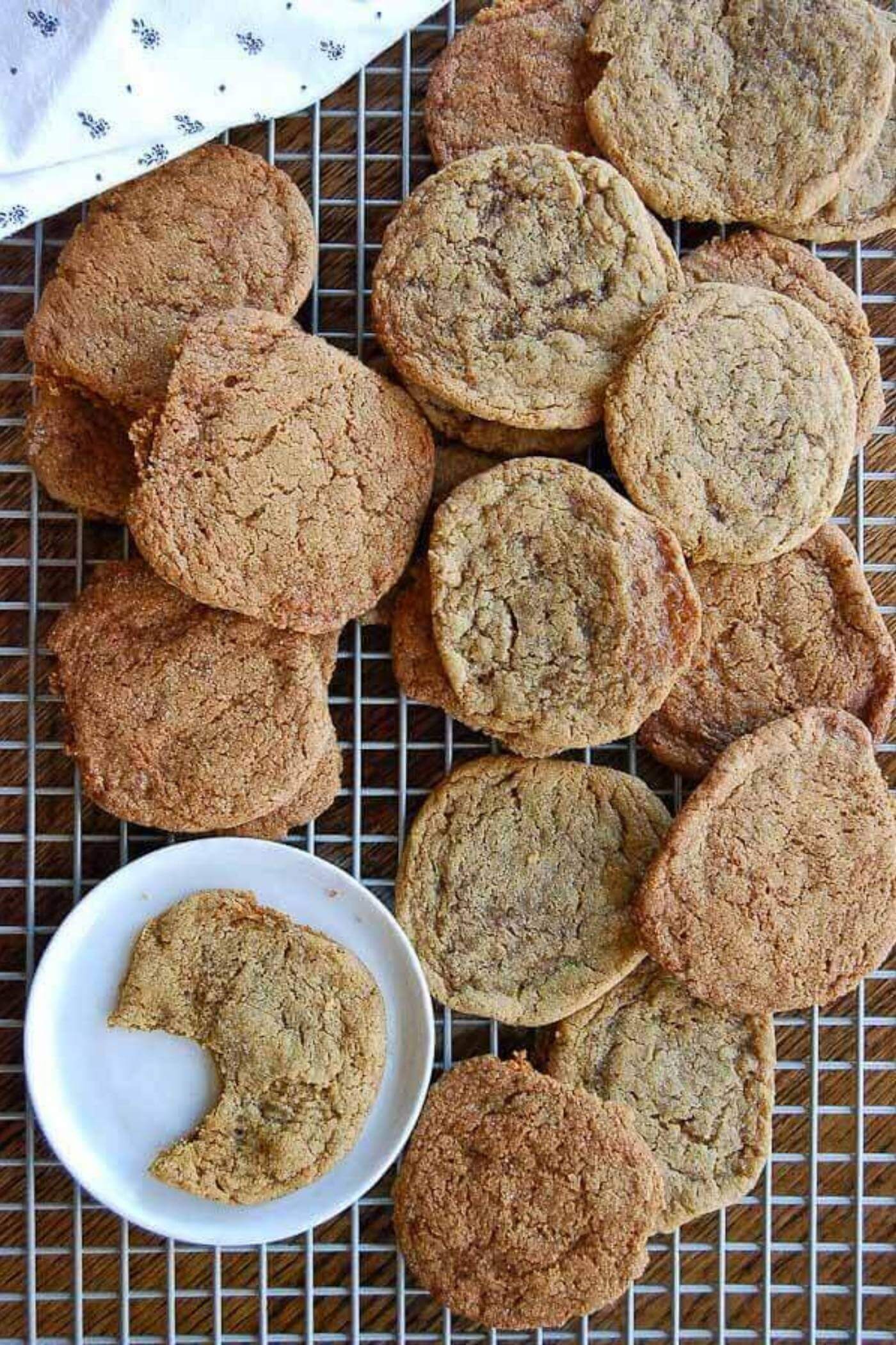 Ginger cookies on cooling rack, with one cookie with a bite taken out on plate.