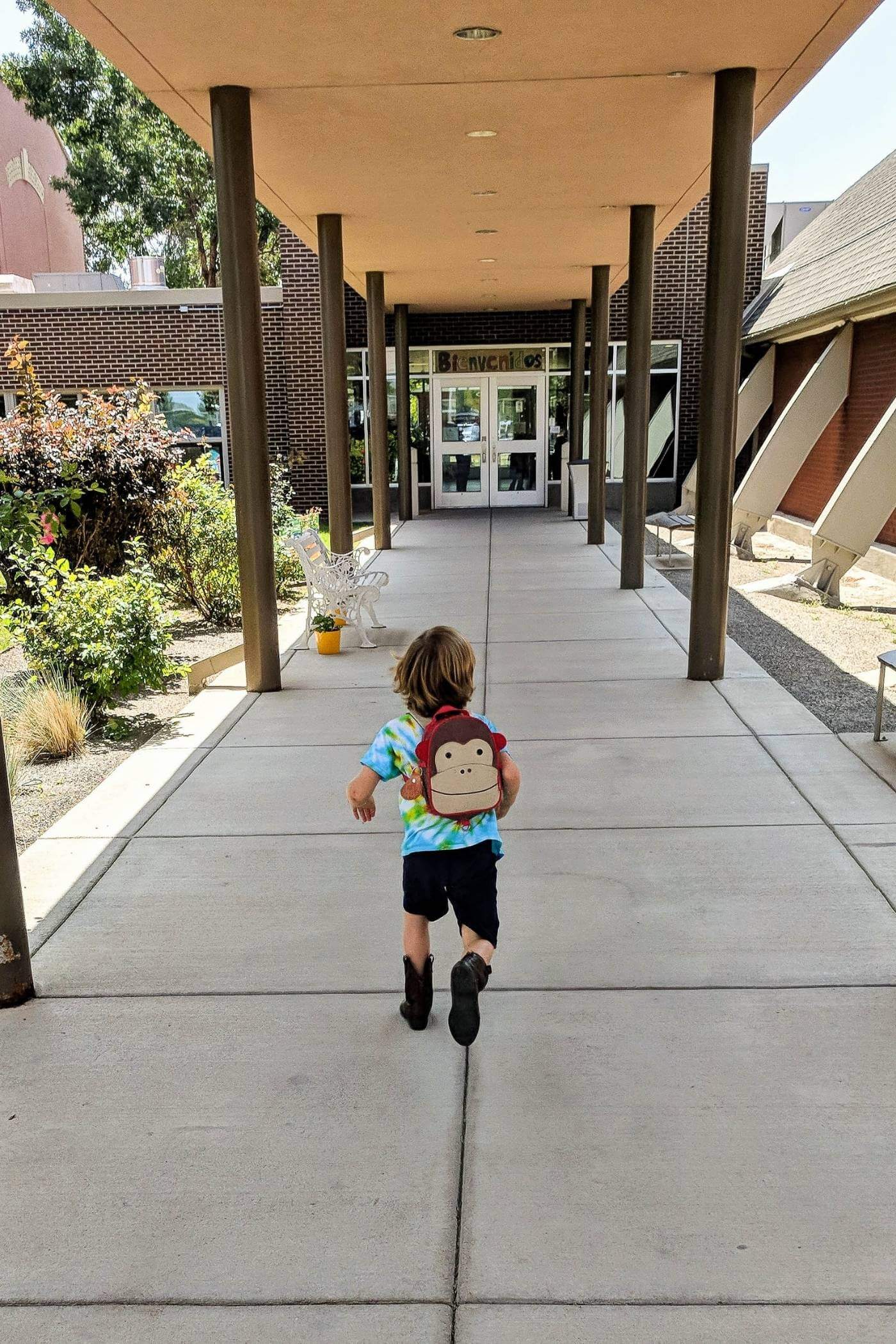 little boy running into school.