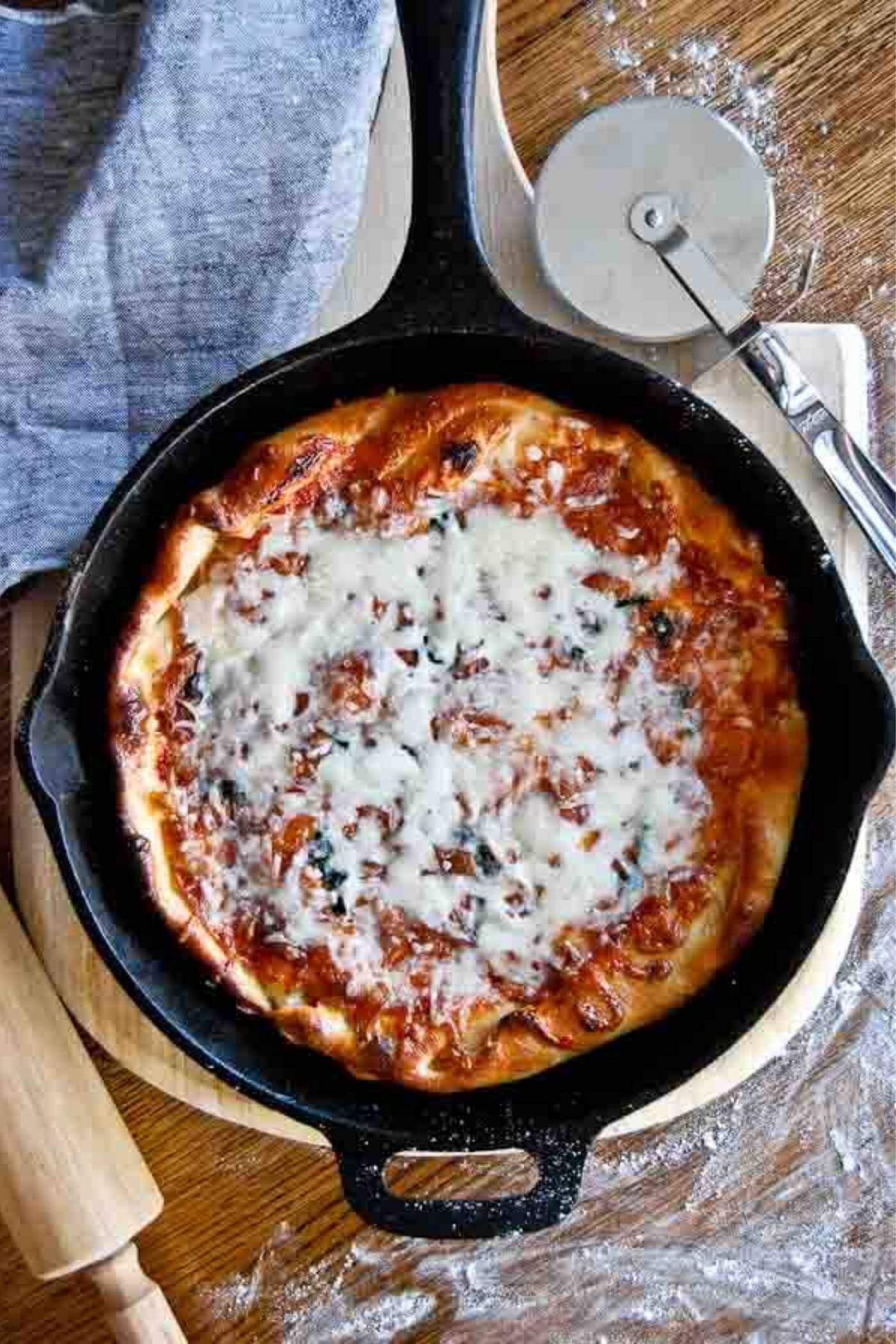 cast iron skillet pizza in pan with pizza cutter.