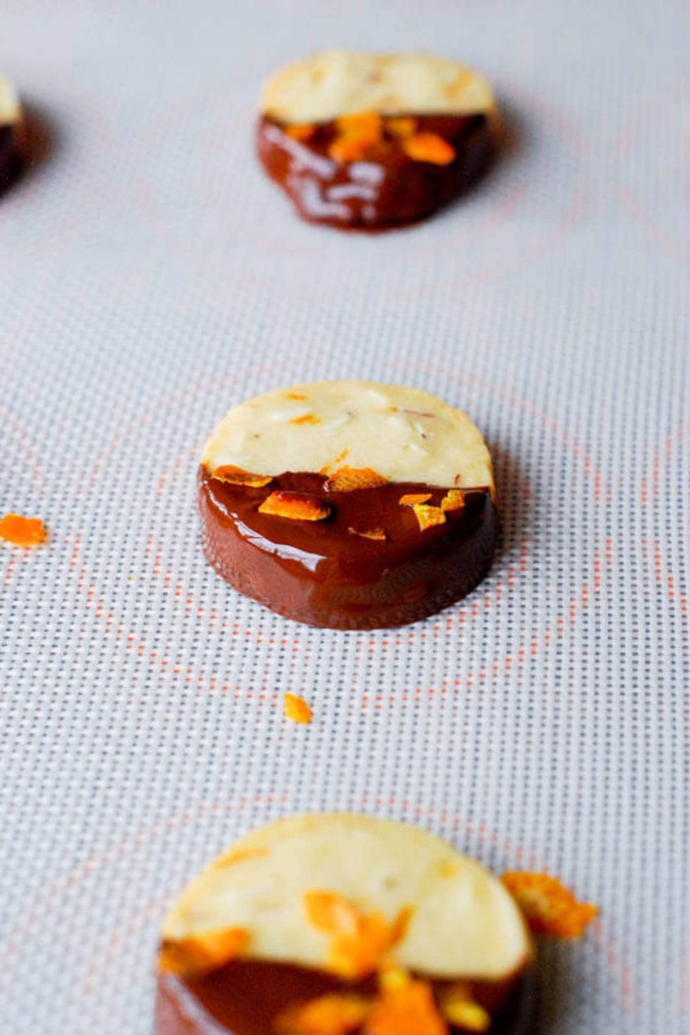 chocolate dipped orange and almond shortbread cookies on baking tray.