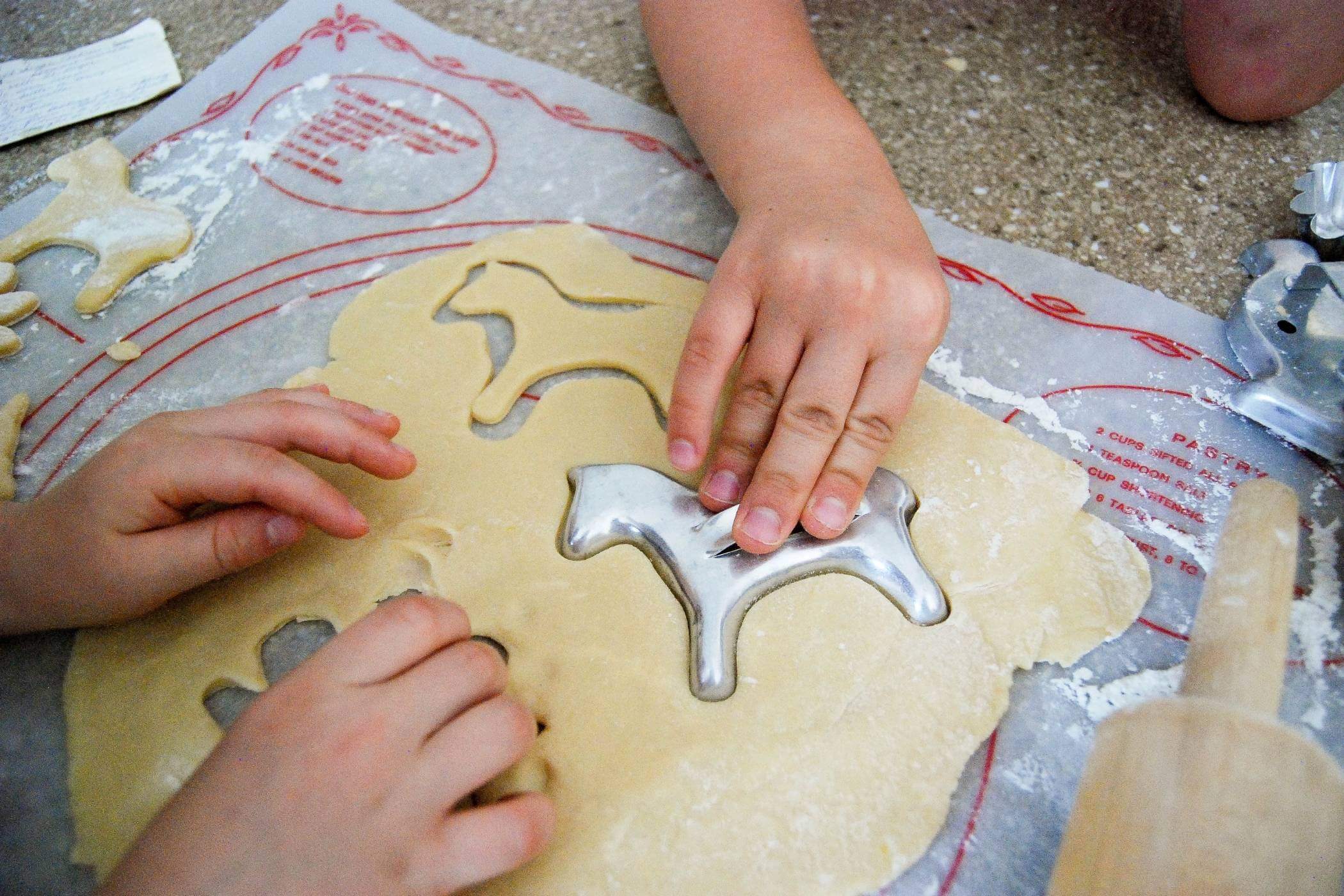 boys using cookie cutters to cut sugar cookies.