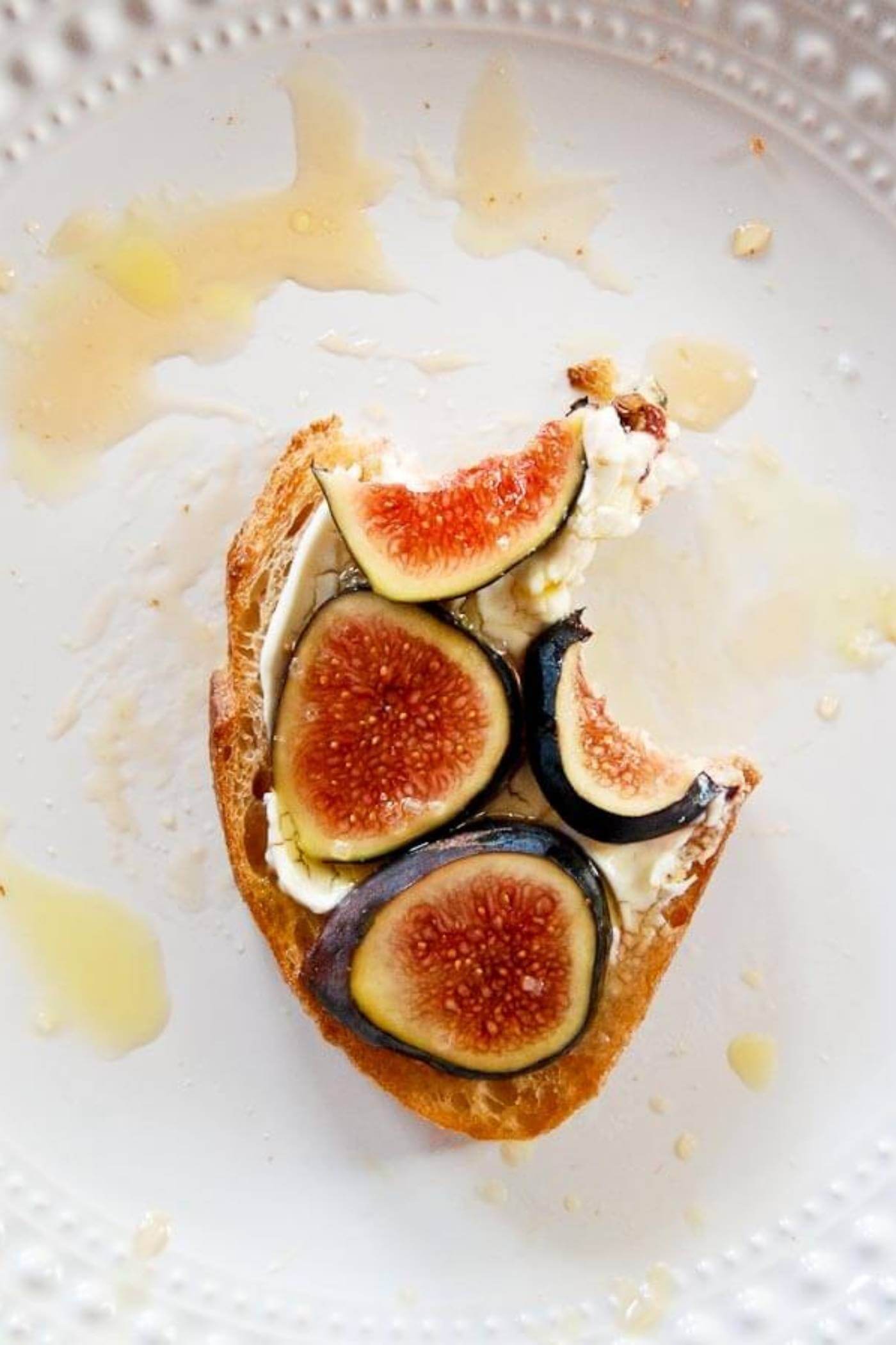 fig and cream cheese toast with bite taken out on plate.