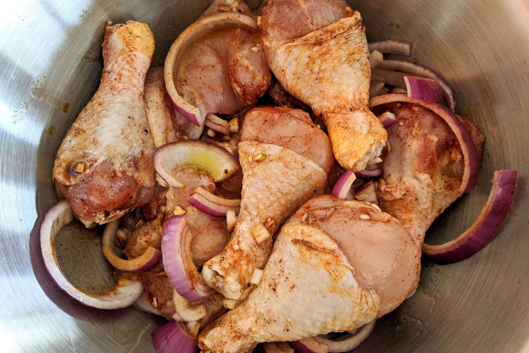 raw seasoned chicken with onions in bowl. 