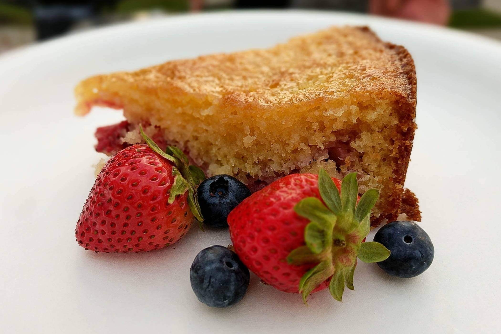 lemon and strawberry cake slice on plate with fresh berries.