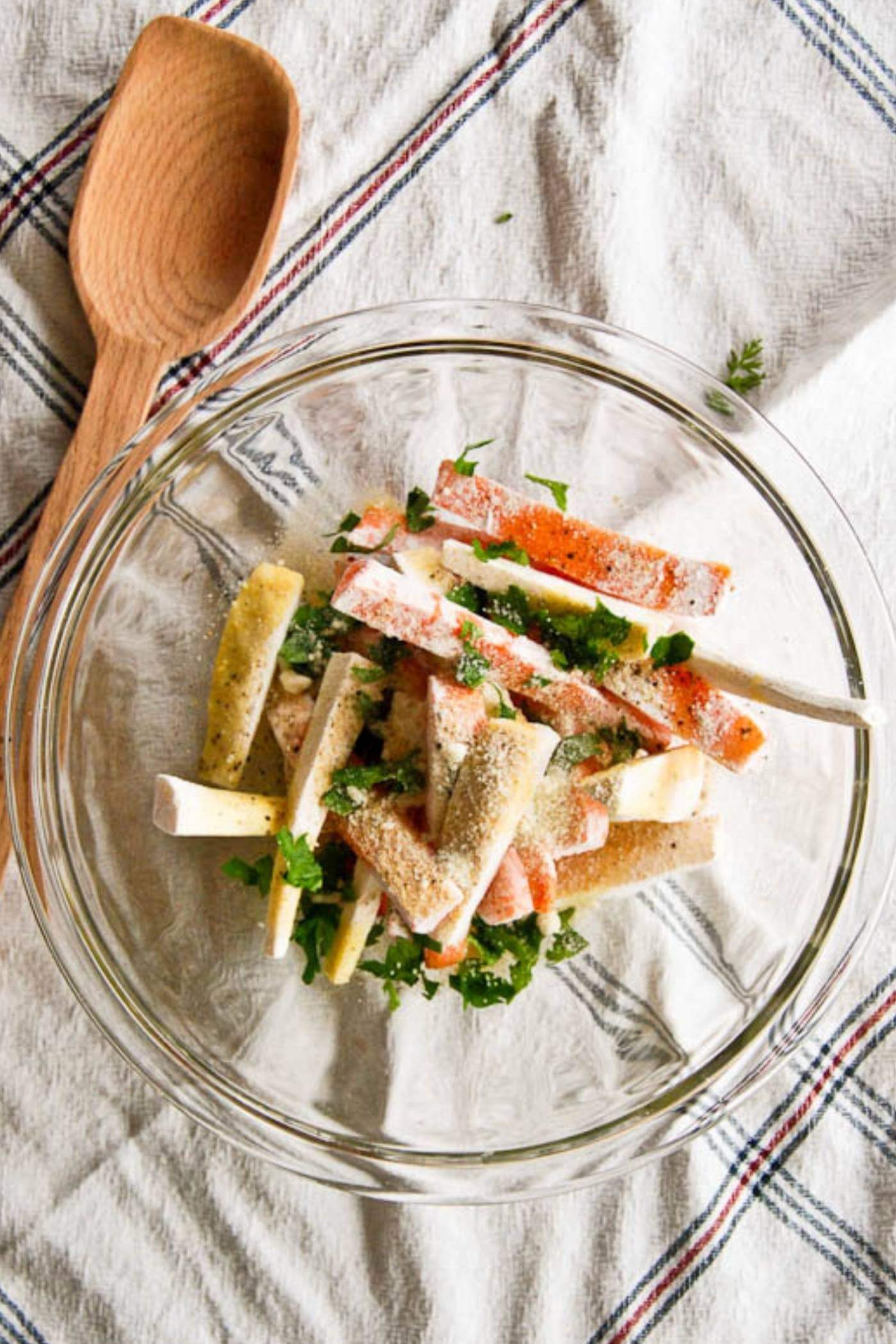 carrot and parsnip fries mixed with parmesan and herbs in bowl.