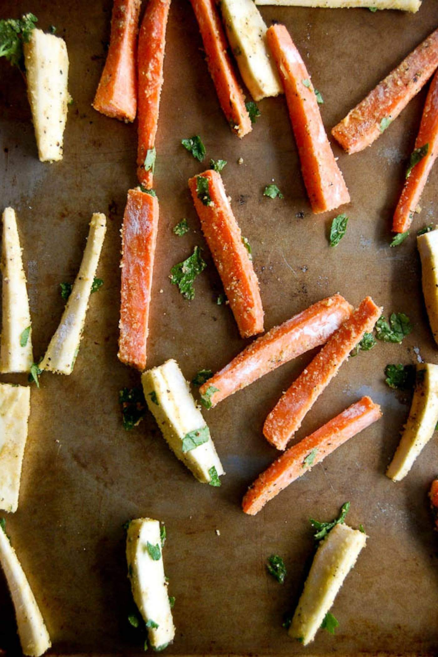 baked parmesan carrot and parsnip fries on baking tray.