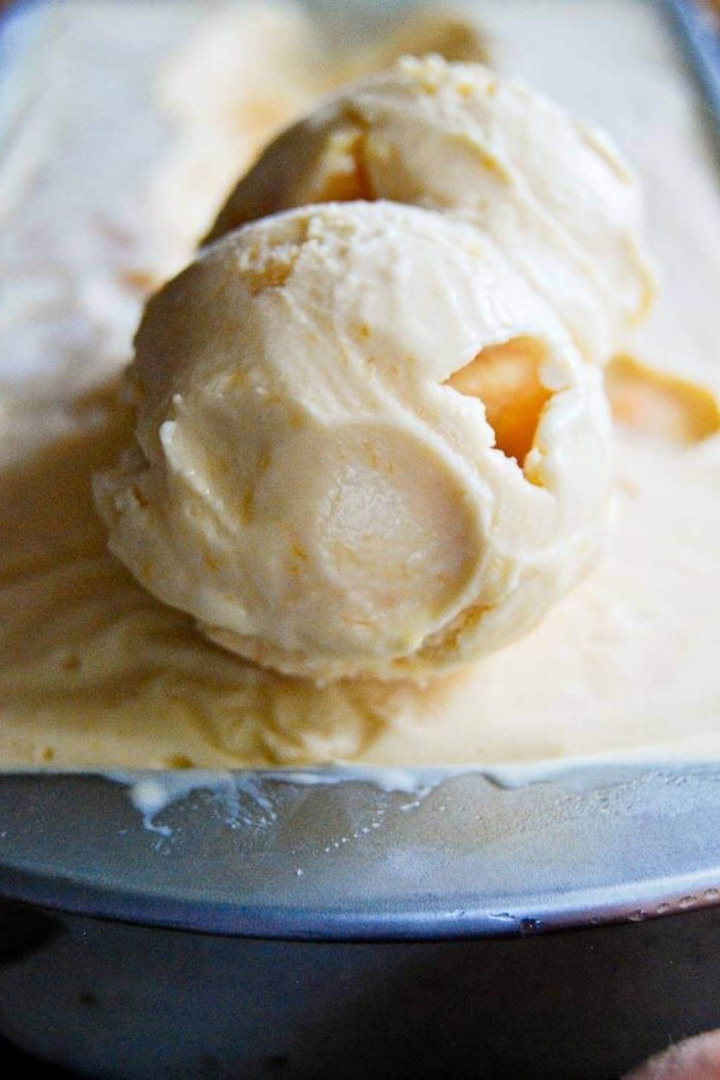 homemade peach ice cream scoops in pan.