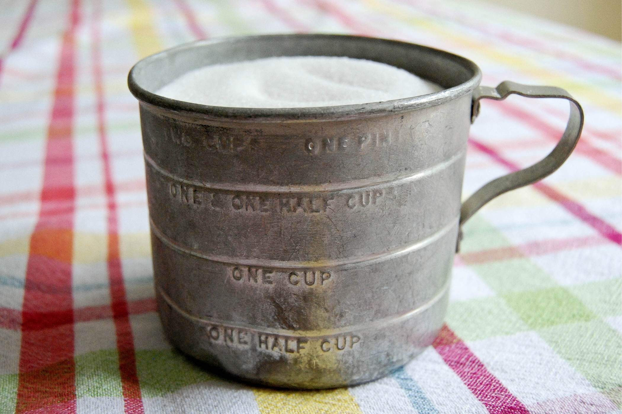 old fashioned measuring cup full of sugar.