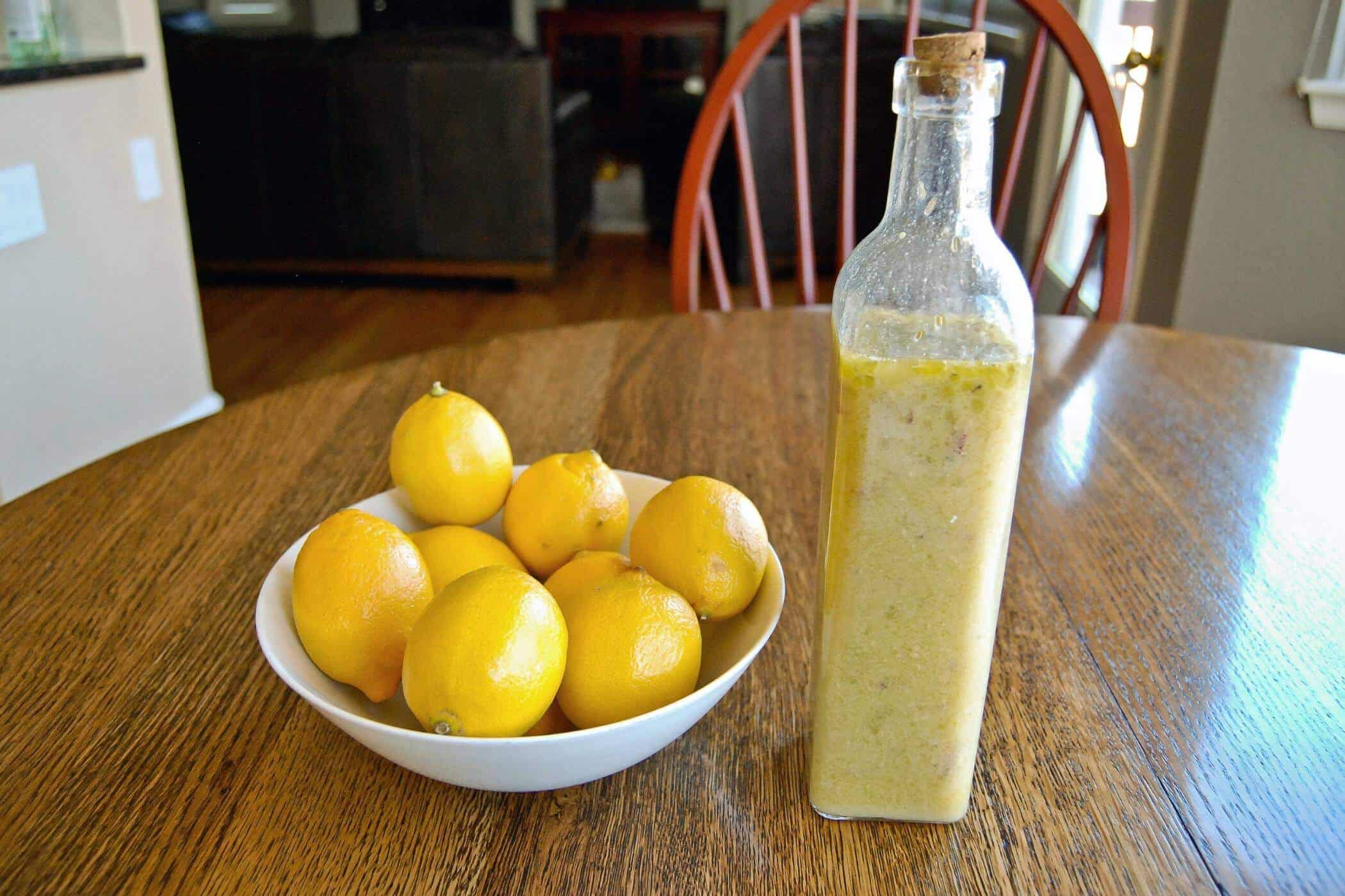 honey lemon vinaigrette dressing in jar next to bowl of lemons.