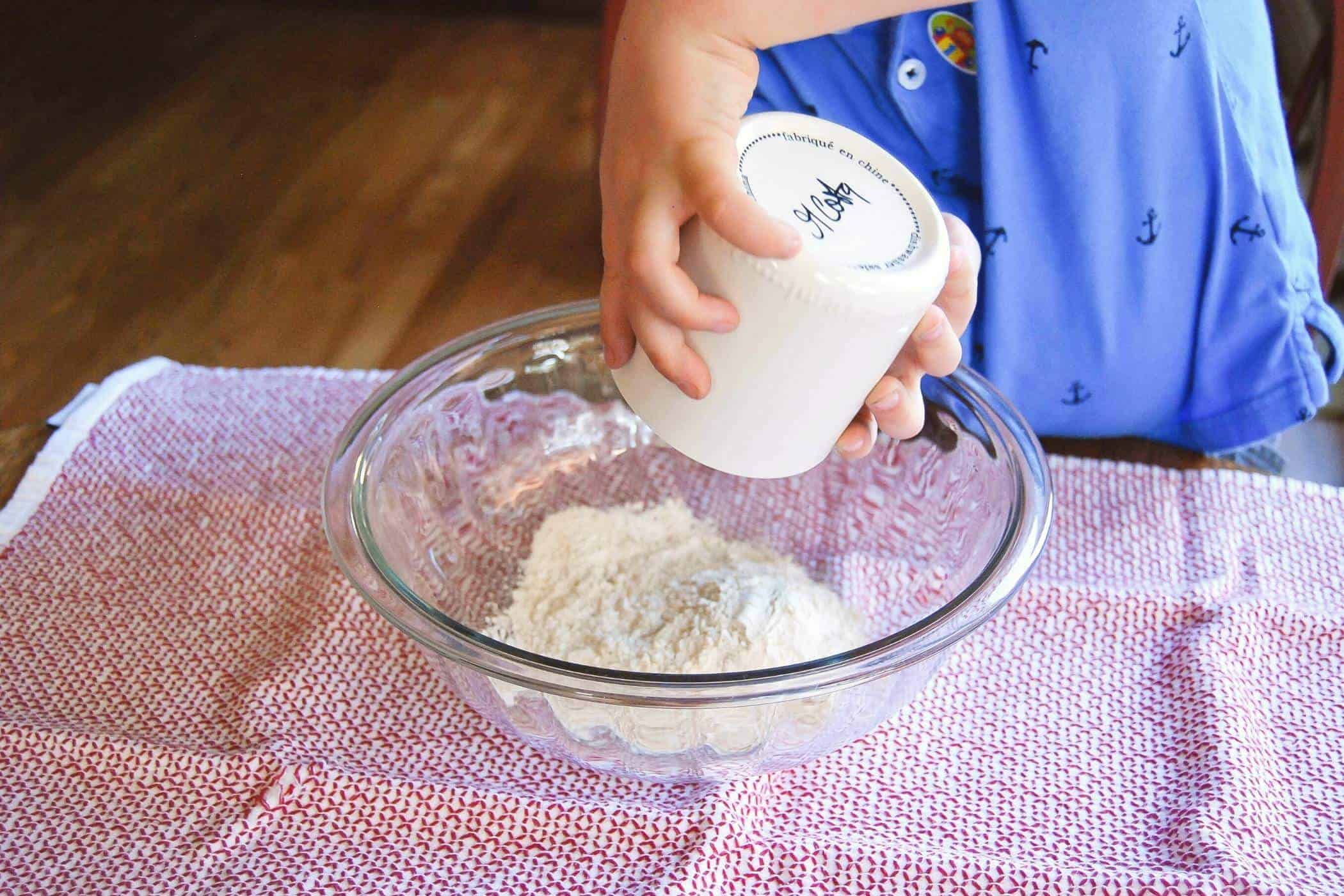 boy pouring flour into bowl.