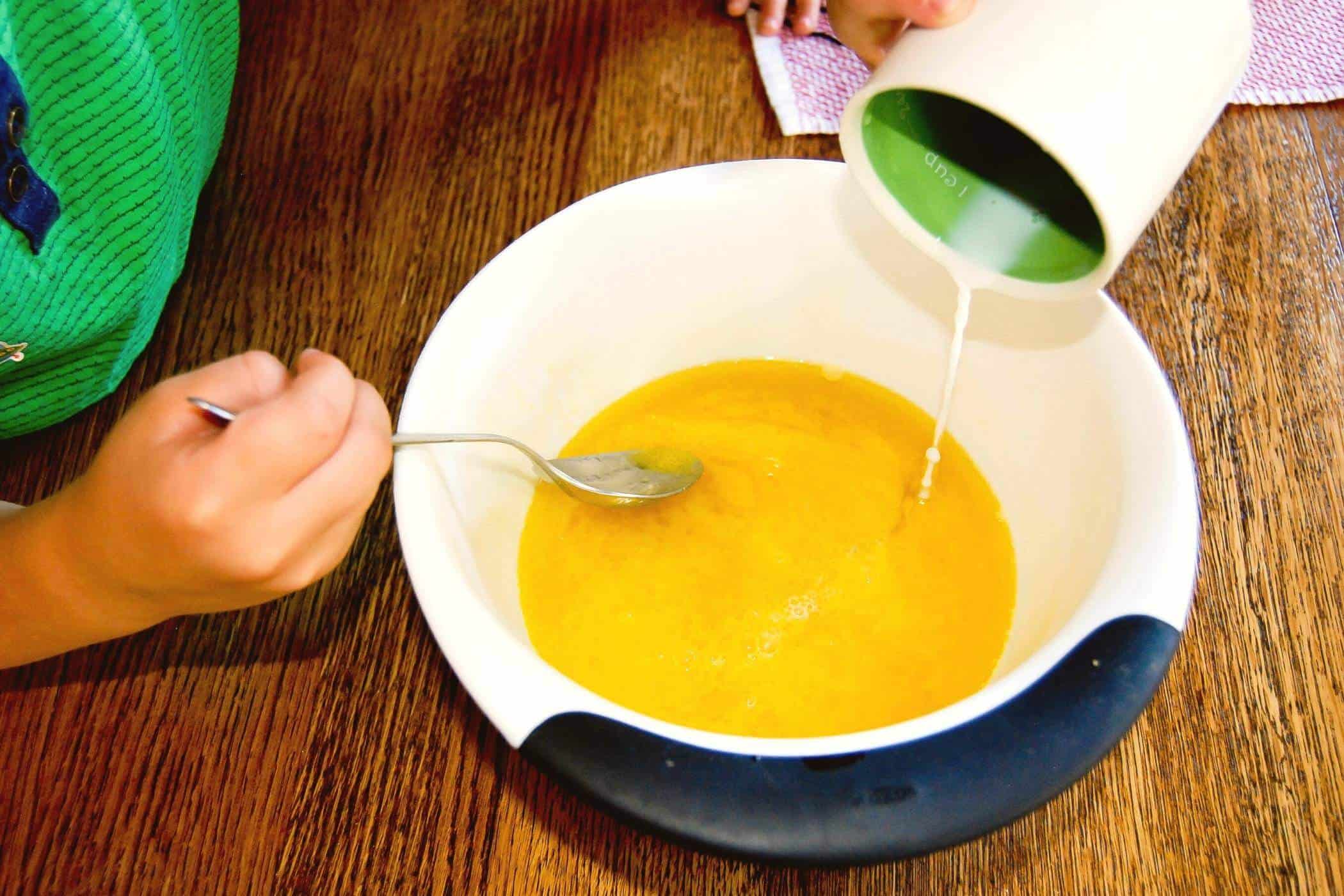 boy mixing milk into eggs.