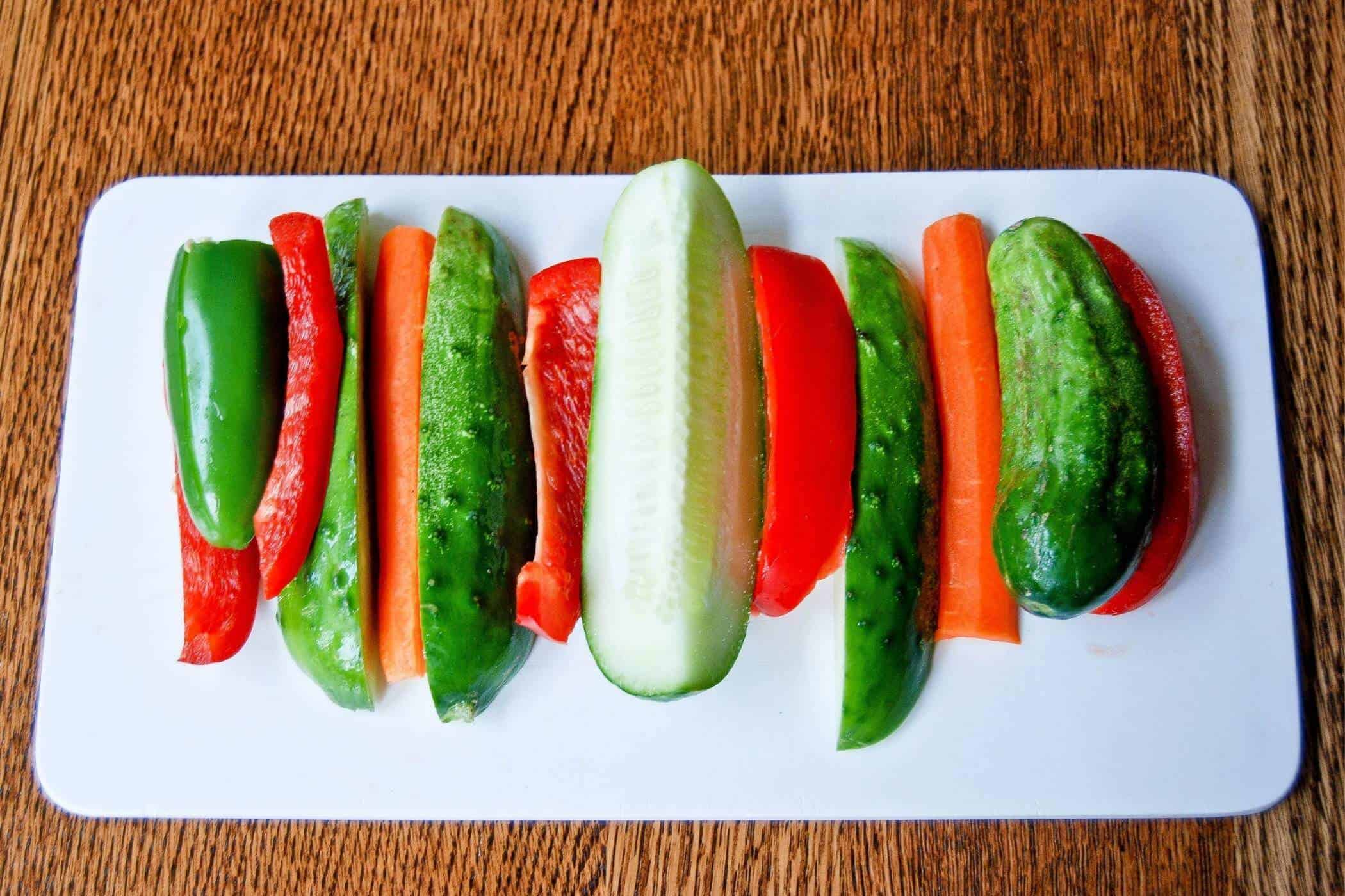 pickling cucumbers and peppers on cutting board.