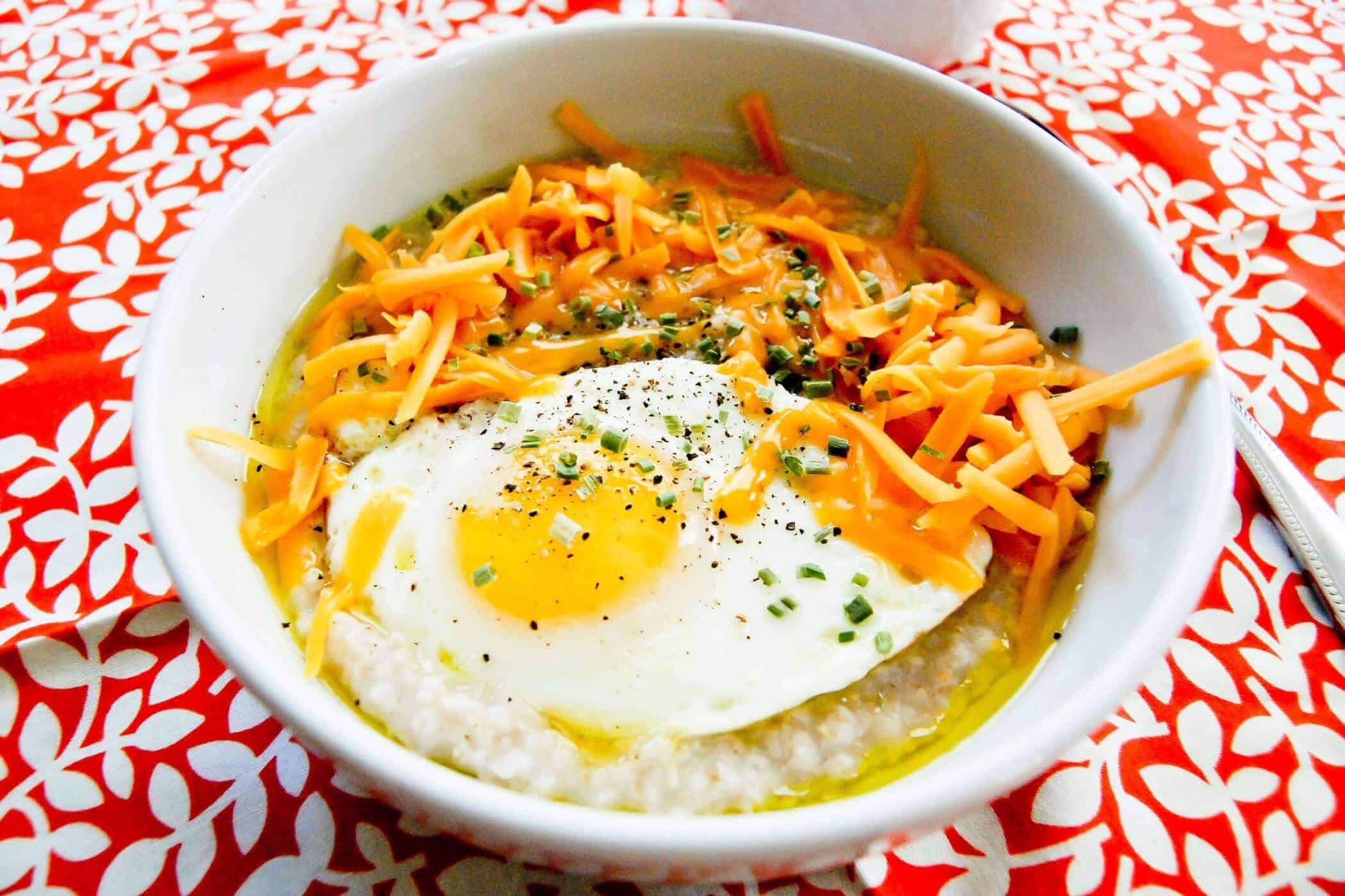 savory steel cut oats with egg, cheese and herbs in bowl.