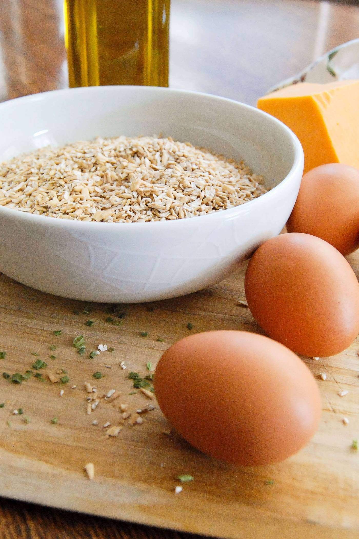 steel cut oats in bowl with whole eggs and block of cheese.