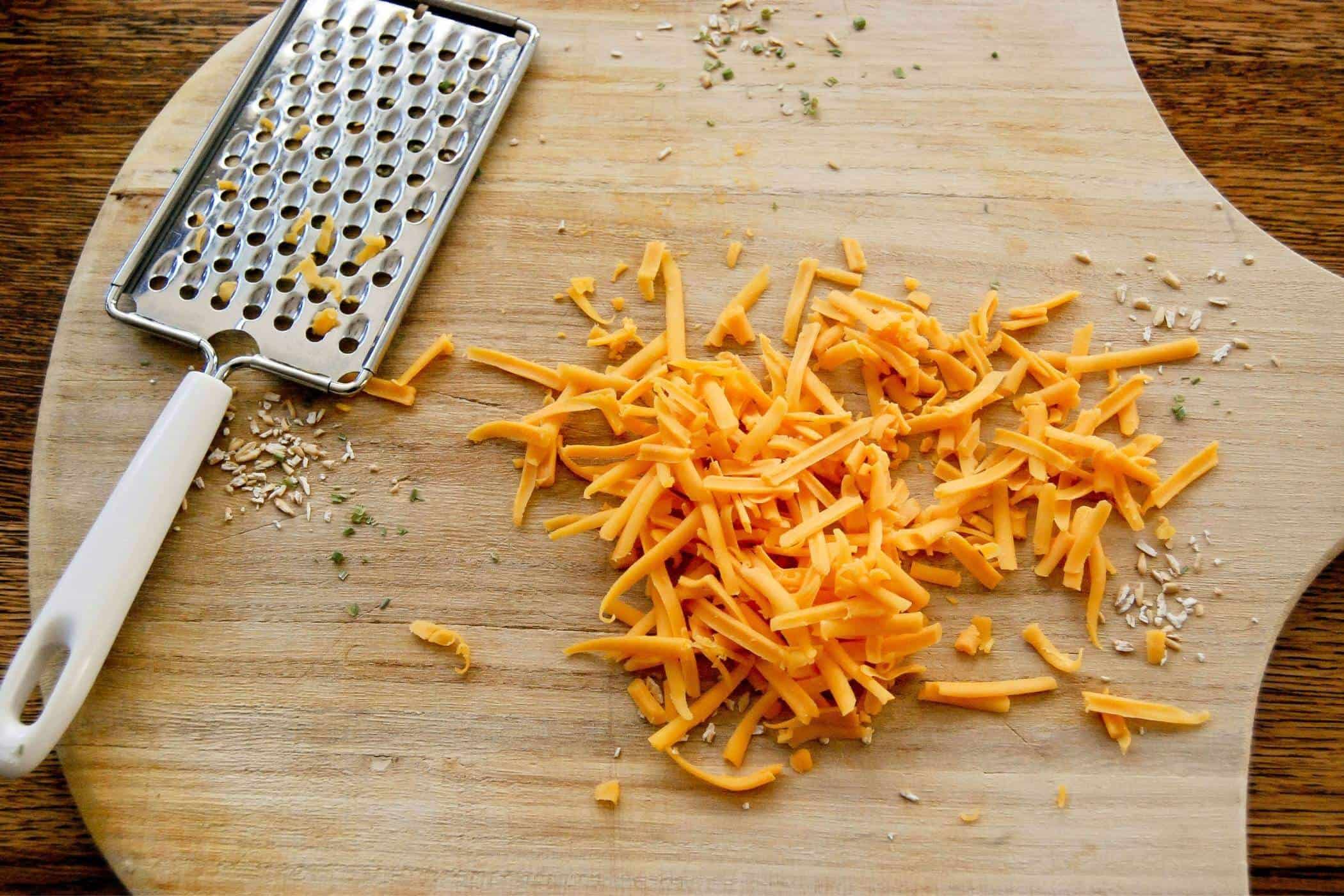 shredded cheddar cheese on cutting board.