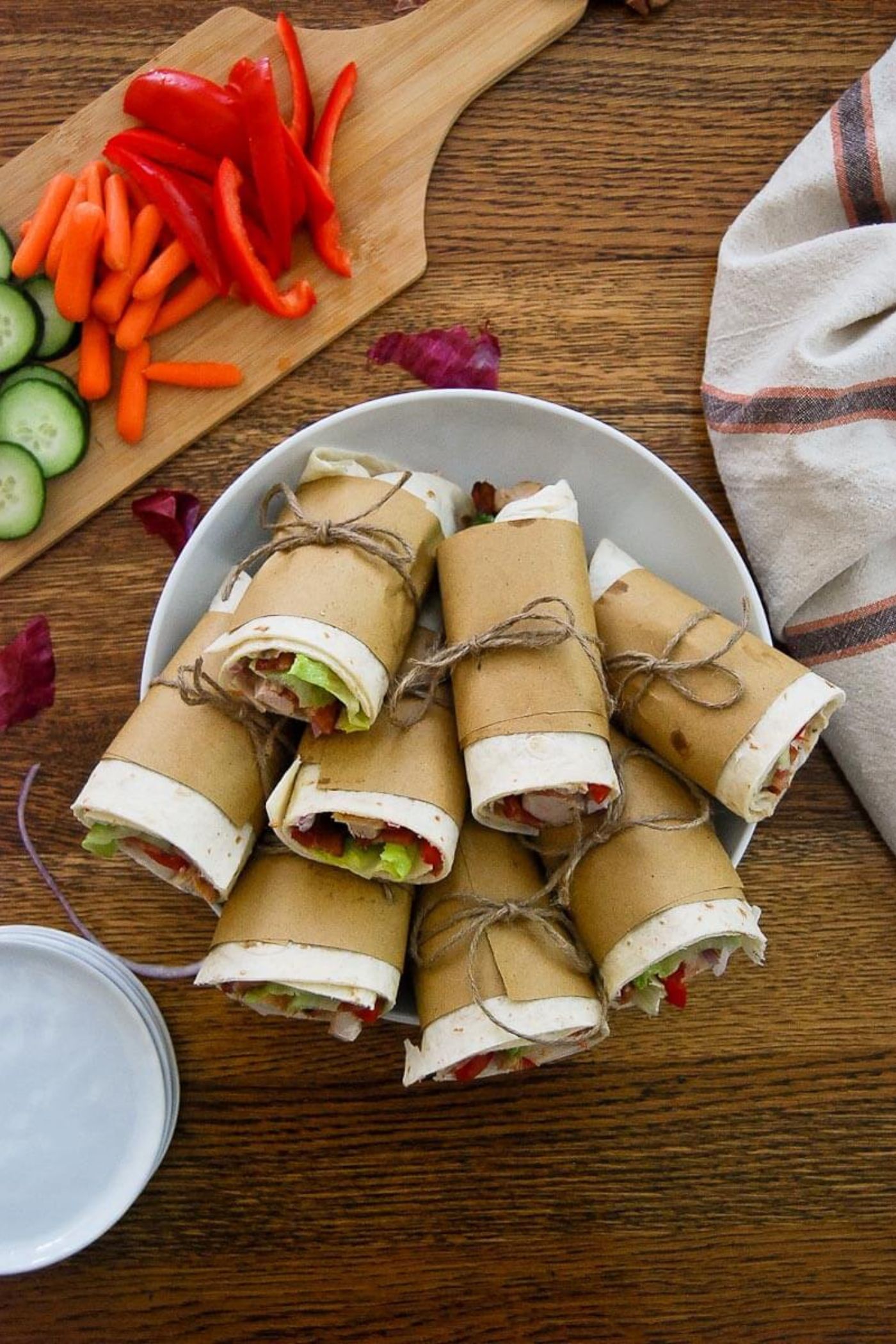 chicken bacon ranch wraps stacked on a plate, tied with paper and string.