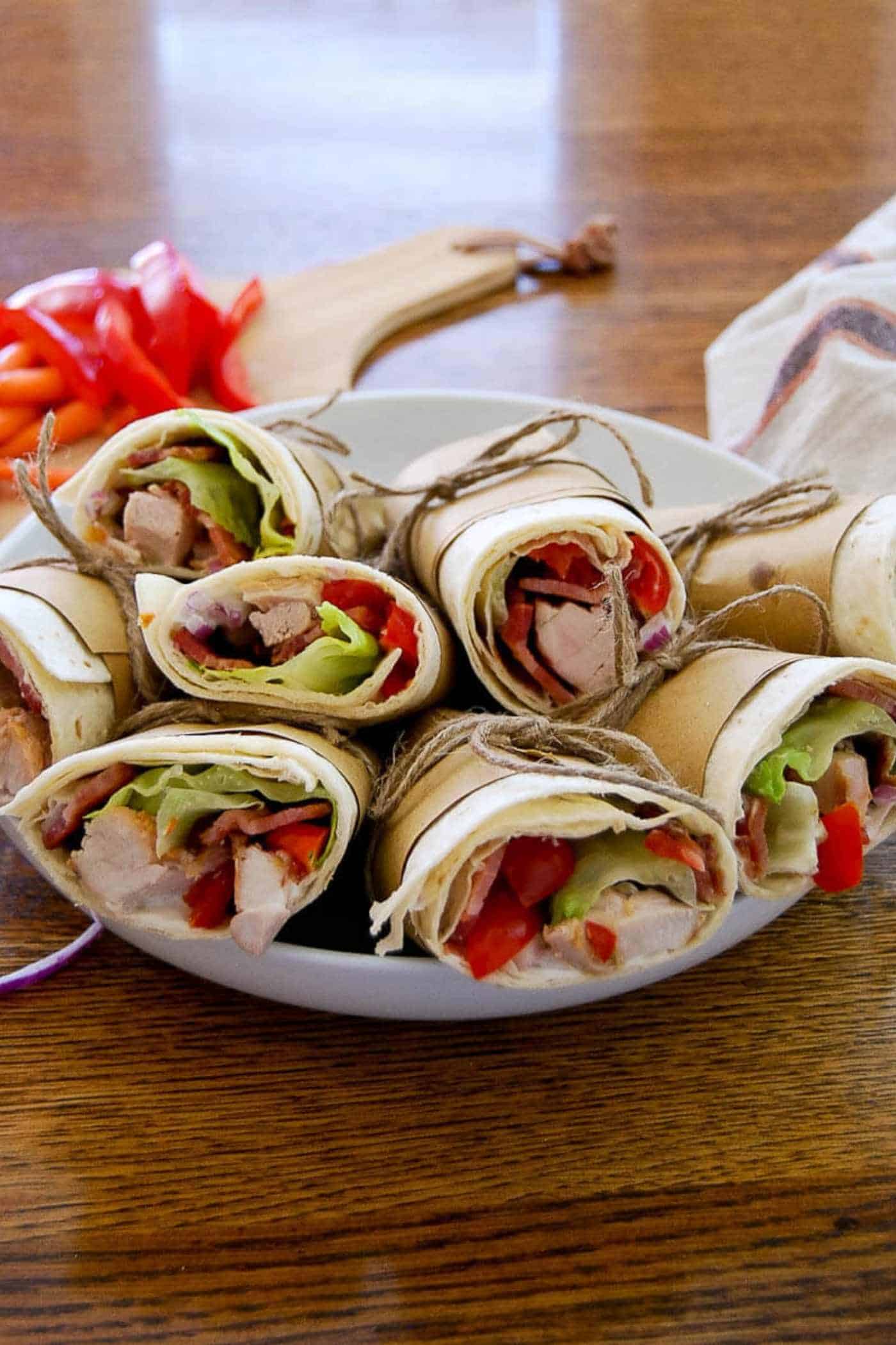 chicken bacon ranch wraps on plate with diced vegetables in background.