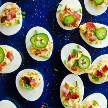 deviled eggs with bacon and jalapeno on tray.