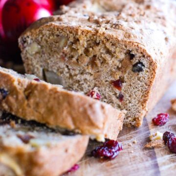 apple cranberry and walnut quick bread on cutting board.