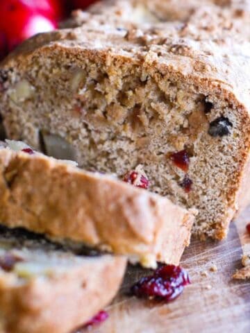 apple cranberry and walnut quick bread on cutting board.