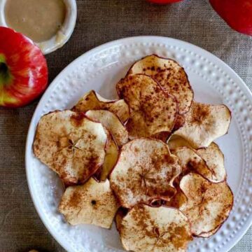 baked apple chips on plate with tahini dressing on the side.