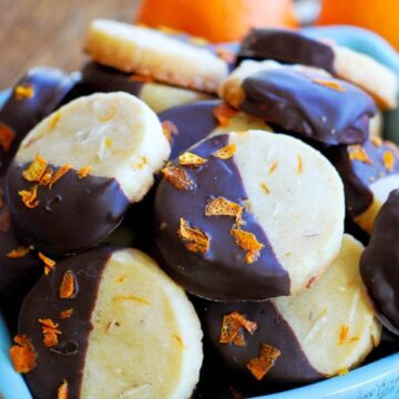 chocolate dipped orange and almond shortbread cookies in bowl.