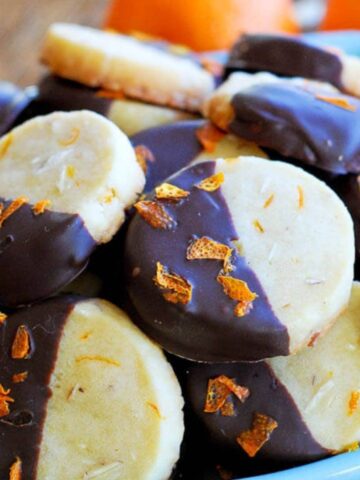 chocolate dipped orange and almond shortbread cookies in bowl.