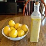 lemon rosemary vinaigrette dressing in bottle next to bowl of lemons.