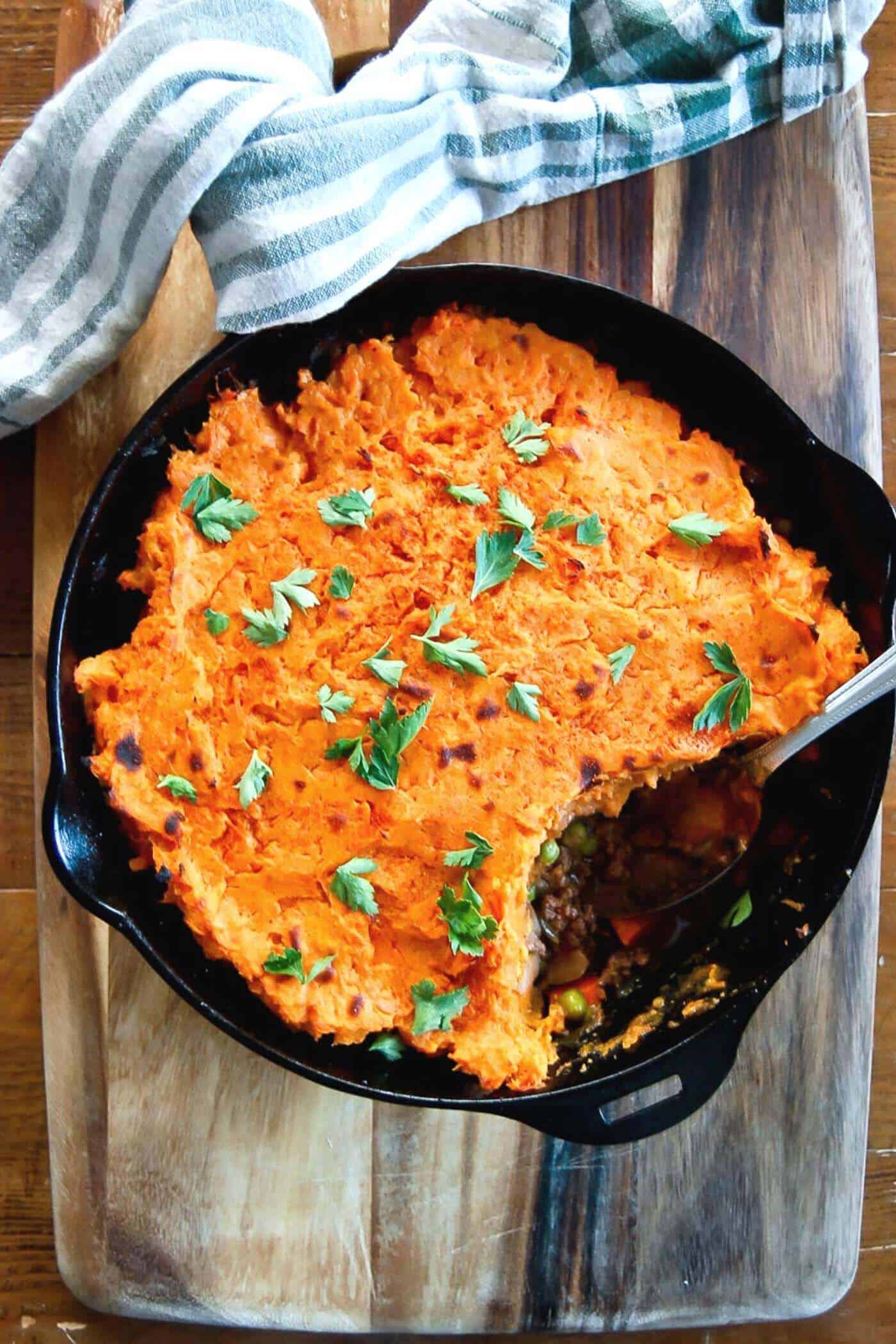 baked sweet potato shepherds pie in skillet with one serving spooned out.