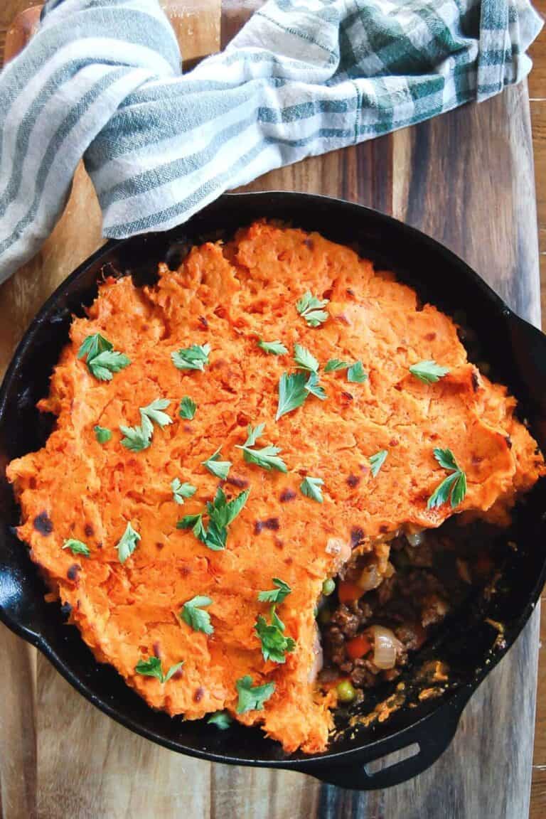 baked sweet potato shepherds pie in skillet with one serving scooped out.