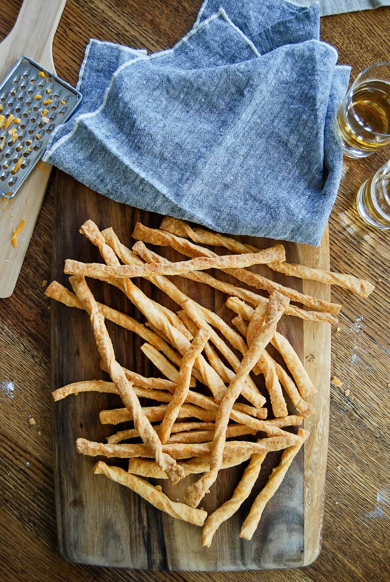 cheddar cheese straws on serving board.