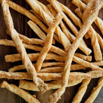 cheddar cheese straws on serving board.