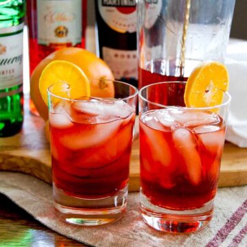 negronis in glasses garnished with orange slices.