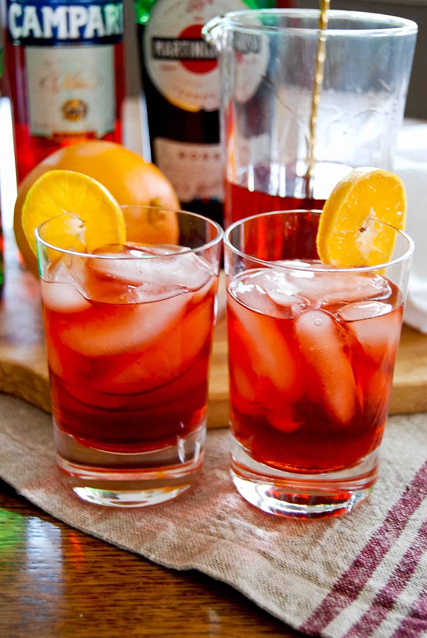 negronis in glasses garnished with orange slices.